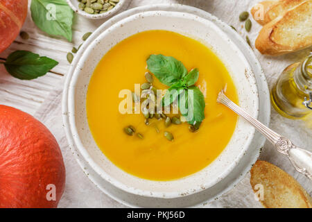 Potiron soupe végétarienne diététique crème purée à l'huile d'olive, des graines de basilic et d'une table en bois dans une assiette blanche. Selective focus Banque D'Images