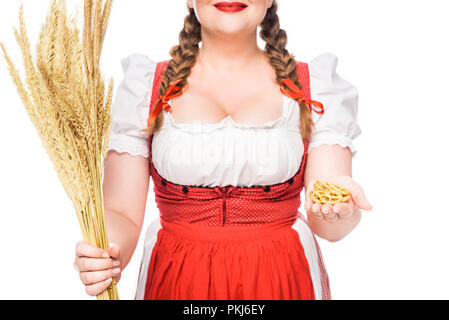 Image recadrée de serveuse oktoberfest en robe traditionnelle allemande montrant peu de bretzels et holding wheat isolé sur fond blanc Banque D'Images