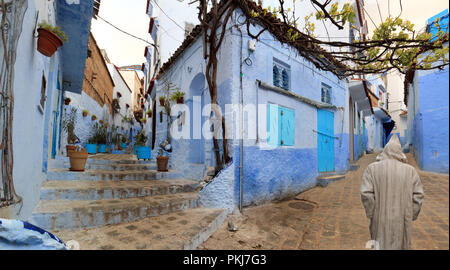 Homme méconnaissable sur son dos avec une tenue typiquement marocain en se promenant dans les ruelles de Chefchaouen, l'une des plus villes touristiques du nord de Mor Banque D'Images