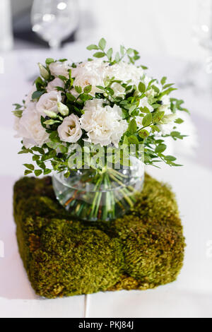 Belle décoration exquise et de la célébration du mariage. Arrangement floral de fleurs blanches et de bleuets verts, dans un vase boule en verre Banque D'Images