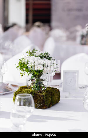 Belle décoration exquise et de la célébration du mariage. Arrangement floral de fleurs blanches et de bleuets verts, dans un vase boule en verre Banque D'Images