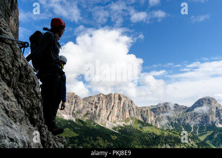 Deux jeunes alpinistes en silhouette sur une pente raide et exposé grimper dans les Dolomites de l'Alta Badia en Italie avec une vue magnifique de la Val Gardena être Banque D'Images