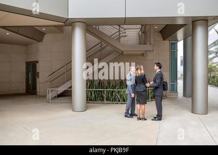 Trois cadres de parler à l'intérieur de leur immeuble de bureaux Banque D'Images