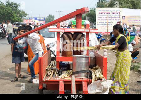 Homme de la région de faire boire du jus de canne à sucre artisanal en bois traditionnel avec du jus de canne à sucre Machine concasseur à Nashik Maharashtra Inde Banque D'Images