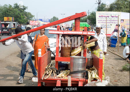 Homme de la région de faire boire du jus de canne à sucre artisanal en bois traditionnel avec du jus de canne à sucre Machine concasseur à Nashik Maharashtra Inde Banque D'Images