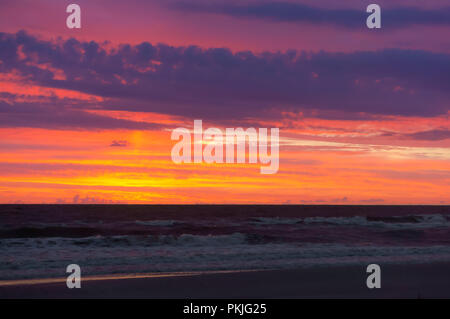 Coucher de soleil sur la mer. Reflet de la lumière du soleil dans les vagues de la mer. Ciel rouge dans les rayons du coucher du soleil. Banque D'Images