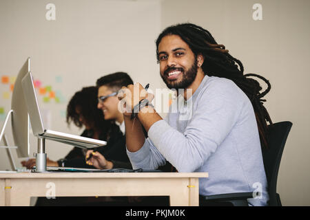 Entrepreneur souriant assis à son bureau avec un ordinateur portable. Business people working in office assis à leur bureau. Banque D'Images