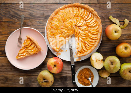 Tarte aux pommes traditionnelle tarte avec de la crème anglaise et de remplissage trappe sur une table en bois rustique. Vue d'en haut Banque D'Images