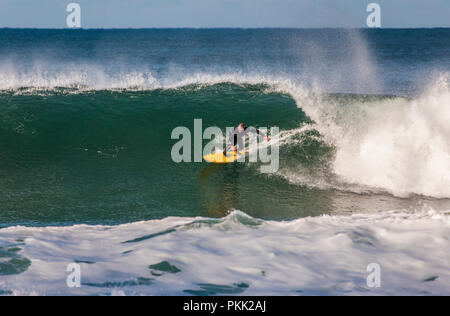 Surfez sur un surf jaune en vous éroulant une grande vague à Bells Beach, Great Ocean Road, Victoria, Australie Banque D'Images