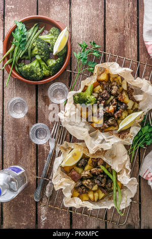 Kleftiko grec traditionnel, un ragoût d'agneau au four avec des pommes de terre, huile d'olive, l'oignon, la carotte, l'ail et fines herbes, servi avec du citron et de l'ouzo. Banque D'Images