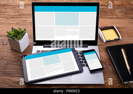 Appareils électroniques avec écran sur un bureau en bois près de journal intime et stylo Banque D'Images