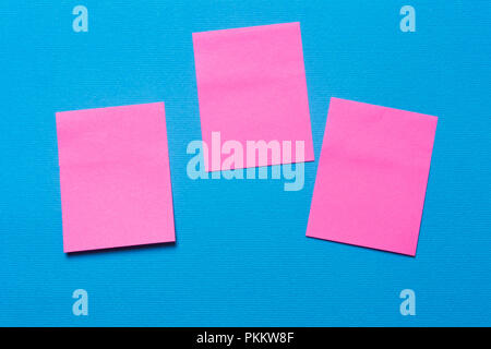 Trois notes rose vide, un autocollant sur un fond bleu pour l'écriture des idées et tâches Banque D'Images