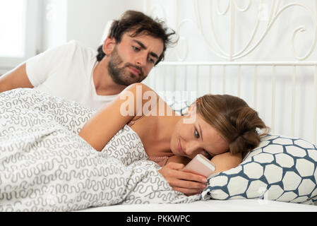 L'homme jaloux vérifie ce qu'une femme avec un téléphone dans la main est en train de faire. Concept de relation, de trahison et de jalousie Banque D'Images