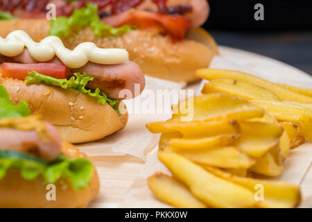 Hot dog avec saucisses grillées et mayonnaise sur un pain frais servis avec frites Banque D'Images