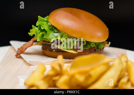 Bacon cheeseburger sur un rouleau frais croustillant de frites sur une planche en bois avec point sélectives pour le burger ! Banque D'Images