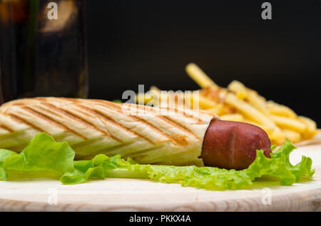 Pain de viande roulé autour assis sur de grandes feuilles en face de floue tas de frites en haut de plateau en bois Banque D'Images