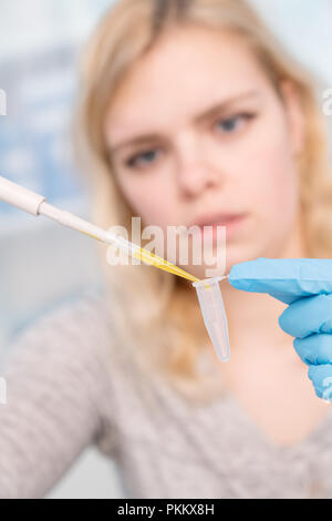 Close up of young female scientist working in genetics laboratory à la pipette dans l'échantillon biologique blanc Banque D'Images