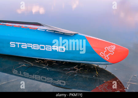 Fort Collins, CO, USA - Le 17 mars 2018 : Arc d'acing stand up paddleboard calme sur le lac au crépuscule - modèle 2018 de All Star SUP par tribord. Banque D'Images