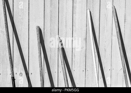 Manches en bois des outils de jardinage en appui sur une clôture. Banque D'Images