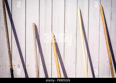 Manches en bois des outils de jardinage en appui sur une clôture. Banque D'Images