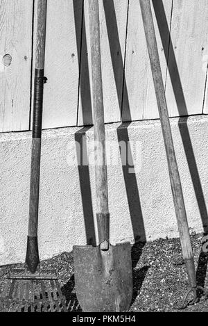 Outils de jardinage en appui sur une clôture. Banque D'Images