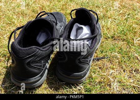 Paire de formateurs noir, ou des chaussures, chaussettes blanches avec à l'intérieur, sur l'herbe à l'extérieur au soleil Banque D'Images