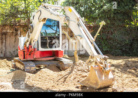 Pelle, pelleteuse travaillant sur le sol pour dégager la zone à côté des arbres pour le nouveau bâtiment du parc Banque D'Images