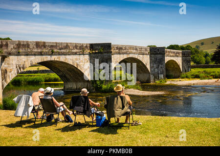 UK, Yorkshire, Wharfedale, Tonbridge, visiteurs détente sur village green au pont sur la rivière Wharfe Banque D'Images