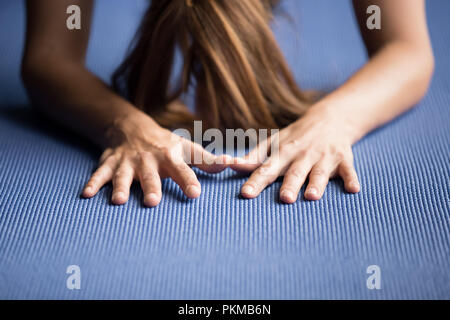 Sporty woman practicing yoga sur un tapis bleu Banque D'Images