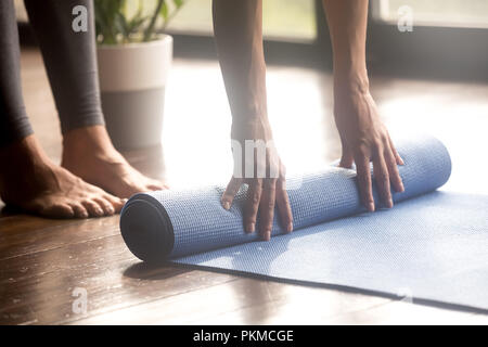 Dérouler le tapis yoga bleu femme, jambes close up Banque D'Images