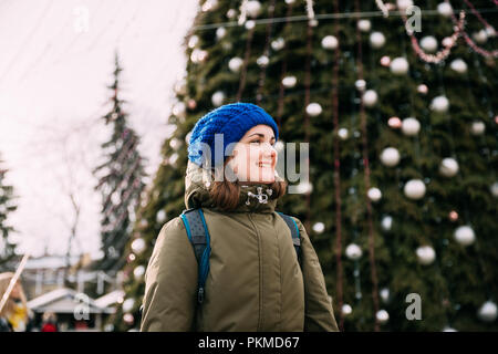 Vilnius, Lituanie. Belle Jeune Fille Femme Pretty Caucasian habillé en vert et bleu Veste Hat s'amusant sur fond arbre Noël. Banque D'Images