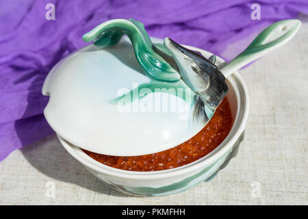 Grand caviar rouge dans une belle icône de porcelaine sur une nappe gris. L'alimentation, de délicatesse Banque D'Images