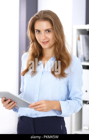 Jeune brunette business woman ressemble à une fille d'étudiant au travail dans bureau. Girl tout droit avec tablette PC. Banque D'Images