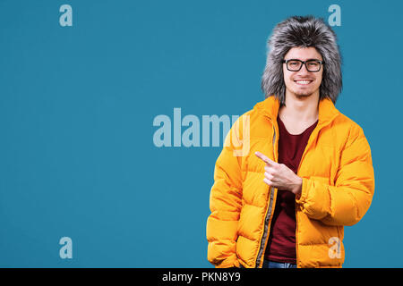 Portrait de jeune homme dans des vêtements chauds sur un fond de couleur. Prêt pour des vacances d'hiver Banque D'Images