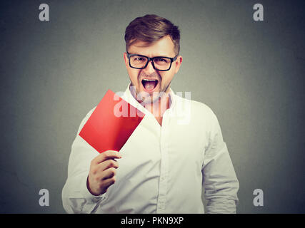 Angry Young man lunettes hurlant de frustration et montrant une carte de mort rouge. Banque D'Images