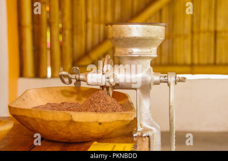 Close up de fèves de cacao et le cacao moulu sur une table en bois, avec moulin manuel, dans un arrière-plan flou Banque D'Images