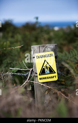 Un signe de détresse jaune informer la population du danger de chute, un puits de mine de la campagne. Banque D'Images