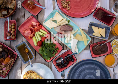 Petit-déjeuner préparé sur la table de bois, fromages, confitures, tomates, concombre, la viande fumée, du beurre, du miel, des olives, des pains Banque D'Images