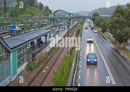 TUMBA, en Suède - le 11 septembre 2018 : le trafic automobile dans la pluie à côté de pistes de banlieue ferroviaire le 11 septembre 2018 à Stockholm, en Suède. Banque D'Images