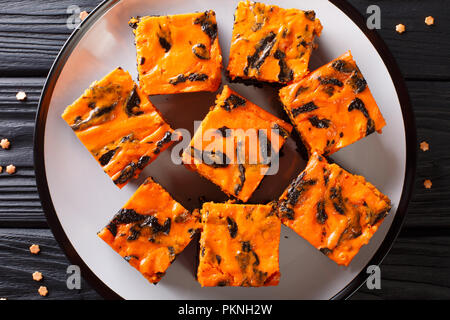 Halloween fête delicious sweet dark brownie gâteau décoré avec de la crème de citrouille orange gros plan sur une assiette. Haut horizontale Vue de dessus Banque D'Images