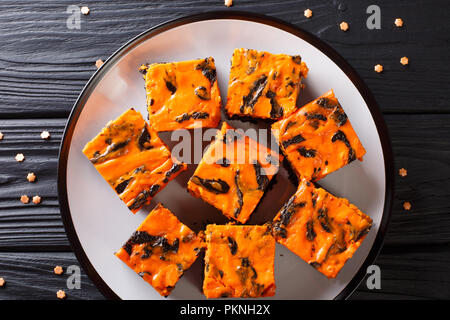 Fromage à la crème dessert Halloween Brownies composé d'un moelleux au chocolat noir garni d'une couche de cheesecake orange gros plan sur une plaque horizontale t. Banque D'Images