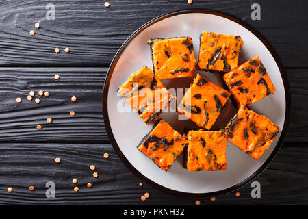 Gâteau de chocolat foncé surmontée d'une couche de cheesecake orange gros plan sur la plaque sur une table. Haut horizontale Vue de dessus Banque D'Images