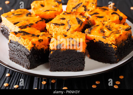 Délicieux dessert gâteau sucré brownie sombre surmontées de cheesecake orange gros plan sur une plaque horizontale. Banque D'Images