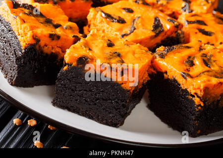 Halloween fête delicious sweet dark brownie gâteau décoré avec de la crème de citrouille orange gros plan sur une plaque horizontale. Banque D'Images