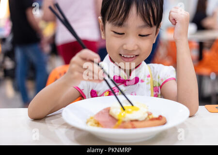 Chinois asiatique little girl eating noodles with chopsticks in restaurant Banque D'Images