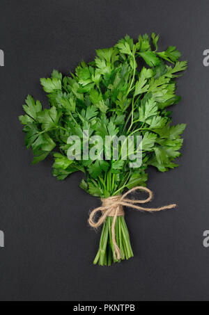 Un bouquet de persil bandé avec une corde avec un arc isolé sur un fond noir Banque D'Images