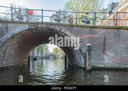 Pont de brique classique avec des vélos sur scène l'un des canaux historiques d'Amsterdam. Banque D'Images