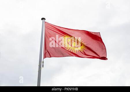 Le Kirghizistan drapeau sur un poteau en agitant sur fond de ciel nuageux Banque D'Images