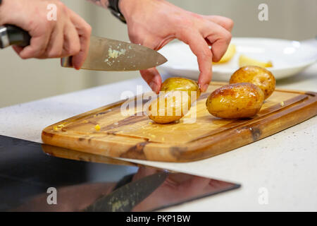 Man slicing mains pomme de terre au four sur planche à découper. La recette pas à pas de plat fait maison Banque D'Images