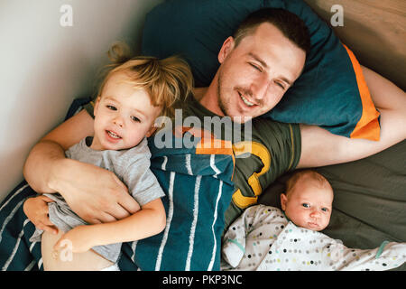 Jeune homme au lit avec les enfants Banque D'Images